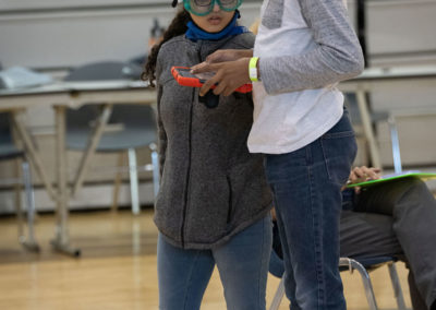 Two students working together to fly a drone from a phone screen
