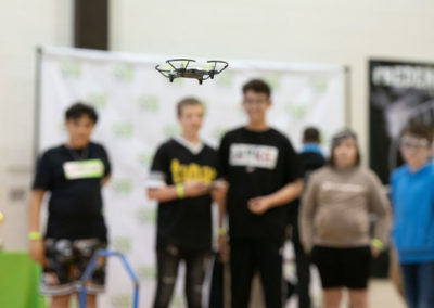 Students in a group flying a drone, with the drone in focus