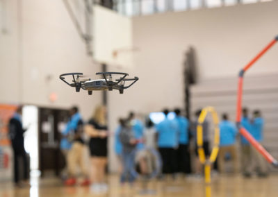 A drone in focus flying around the gymnasium